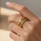 Gold ring with engraved text on a hand against a neutral background